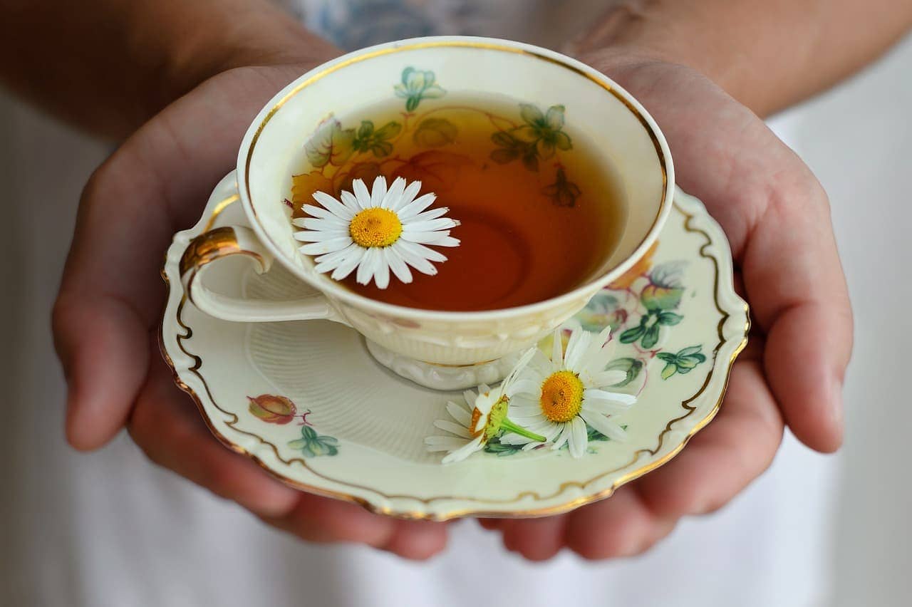 A warm cup of chamomile tea with chamomile flowers and fresh ginger slices, known for easing digestive discomfort naturally.