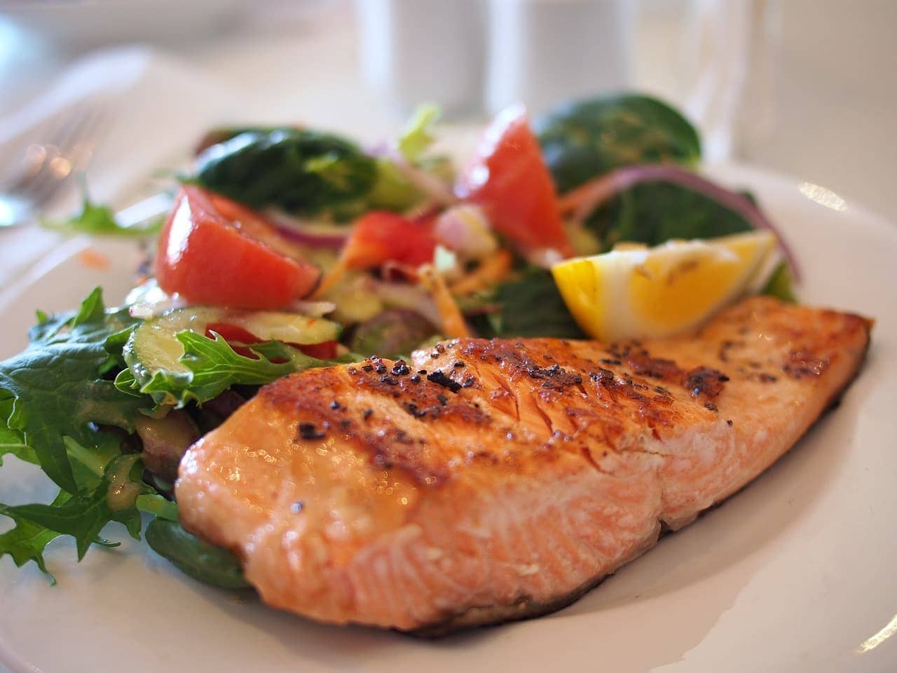 A variety of metabolism-boosting foods like chili, green tea, eggs, and leafy greens arranged on a kitchen counter.